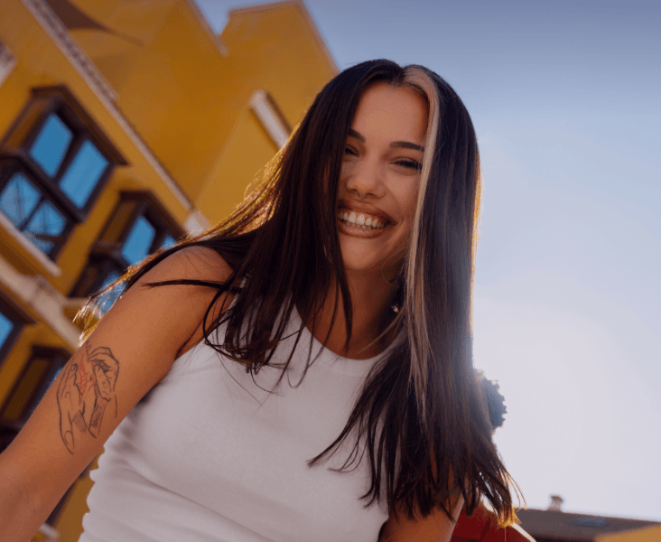 Mujer sonriente con edificio amarillo de fondo